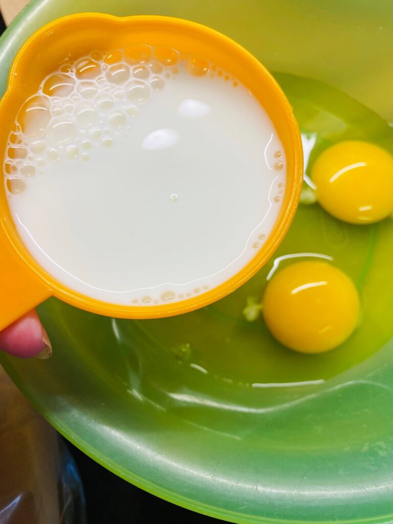 adding milk to the eggs in a bowl