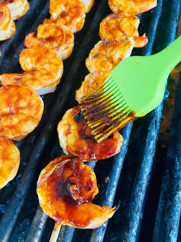 brushing sauce on shrimp on the grill