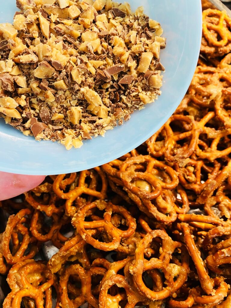 adding more toffee bits to smoked pretzels