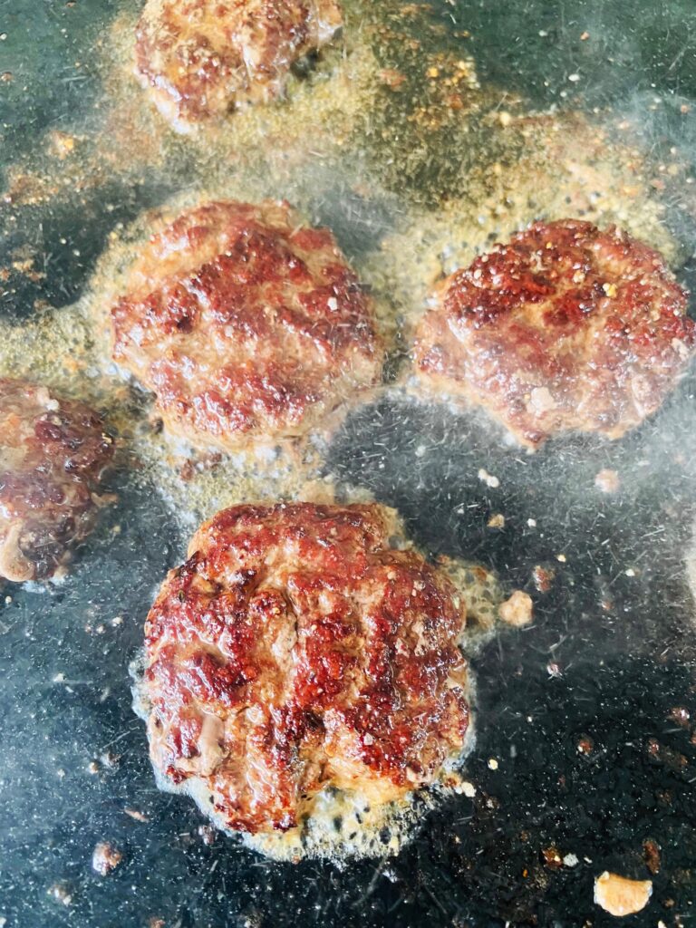mini smashed burgers on the griddle