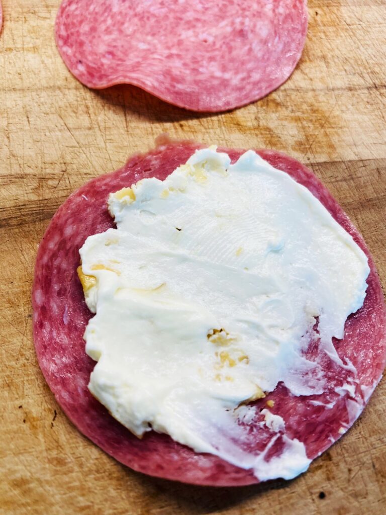 spreading cream cheese on salami