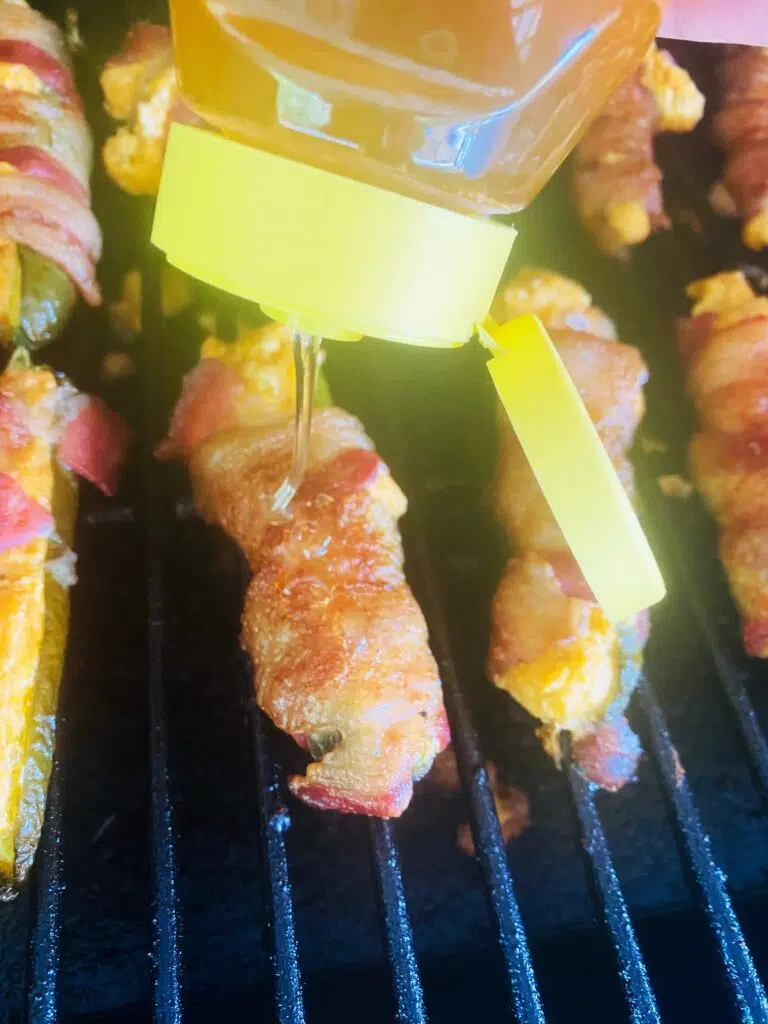 drizzling honey over Smoked Honey Hot Jalapeno Poppers