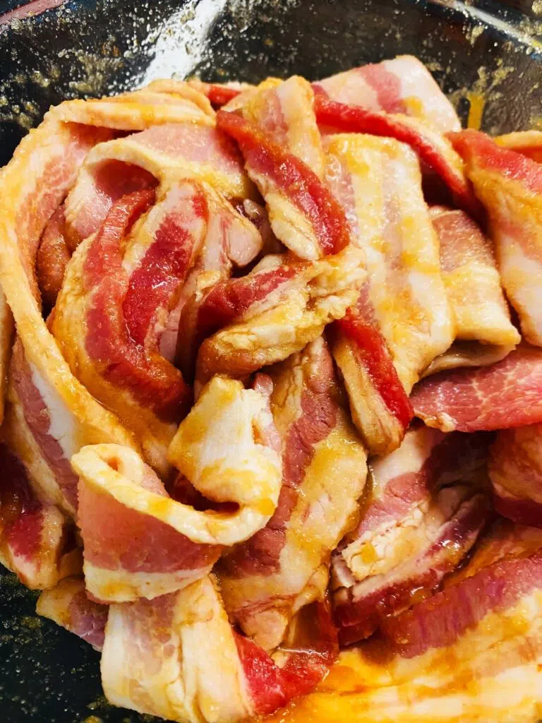 bacon in a bowl coated with the glaze 