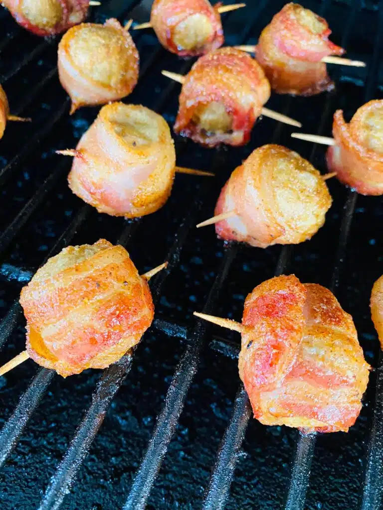 Bacon wrapped meatballs halfway through cooking being flipped over
