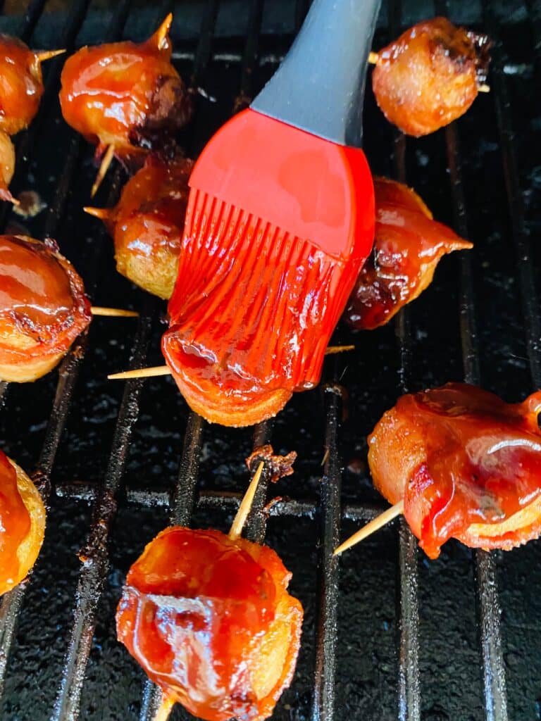Brushing sauce over the smoked bacon wrapped BBQ meatballs