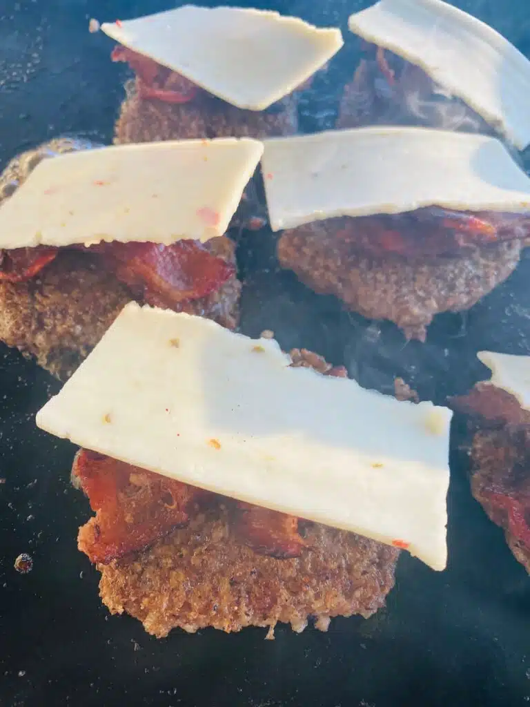Adding bacon and cheese to the goetta on the griddle