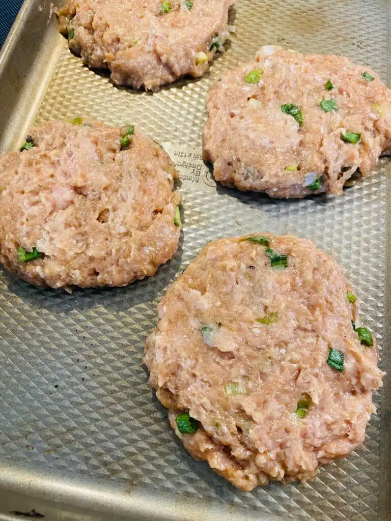 chicken burger patties on a tray before cooking