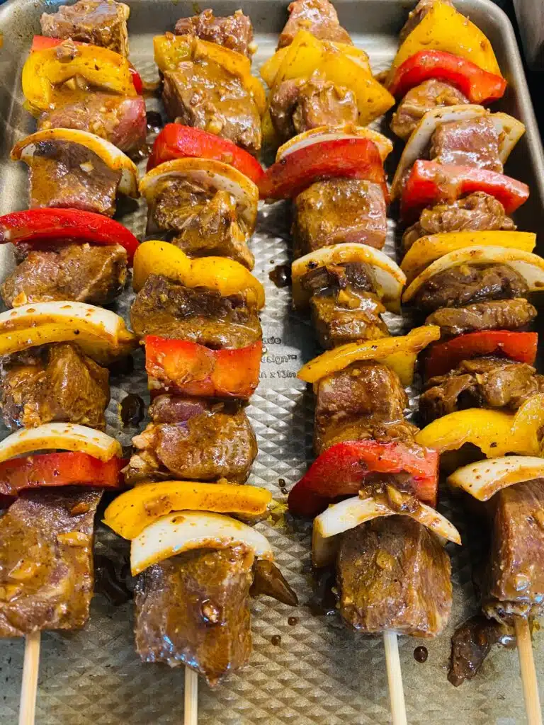 four steak kabobs on a tray before cooking