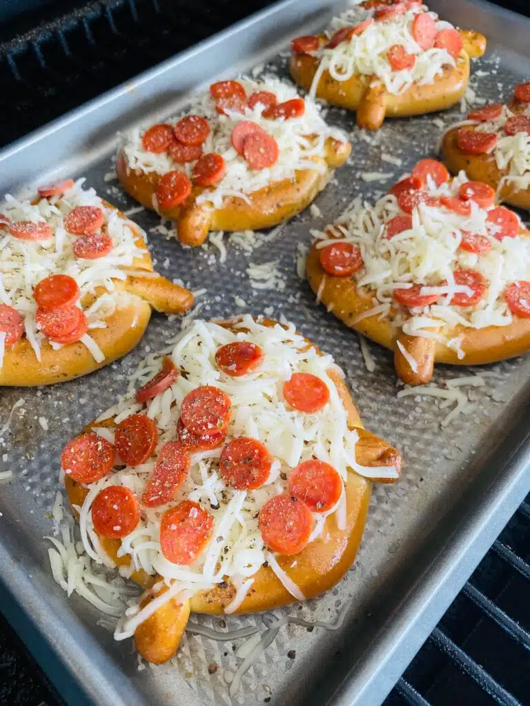 soft pretzel pizzas topped with pepperoni on the smoker