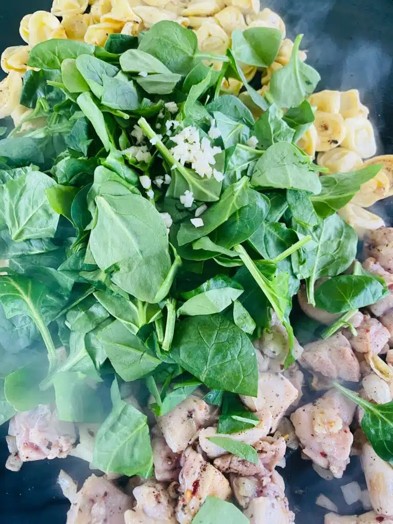 adding fresh spinach to the dish