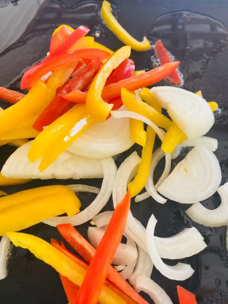 peppers and onions on the griddle before cooking