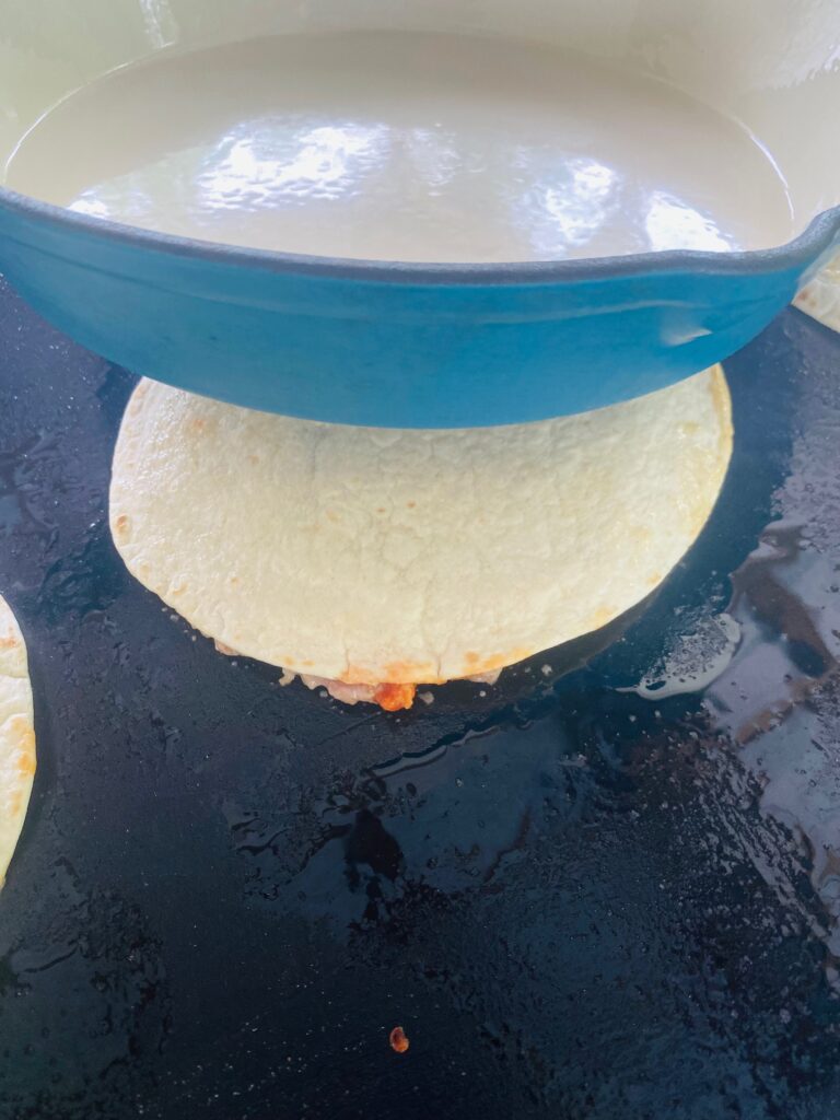 using a cast iron pan to smash the tacos