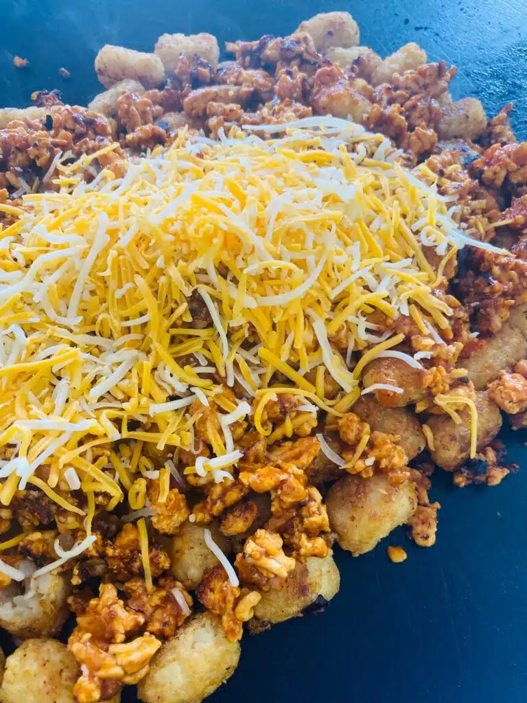 adding cheese to the loaded tots