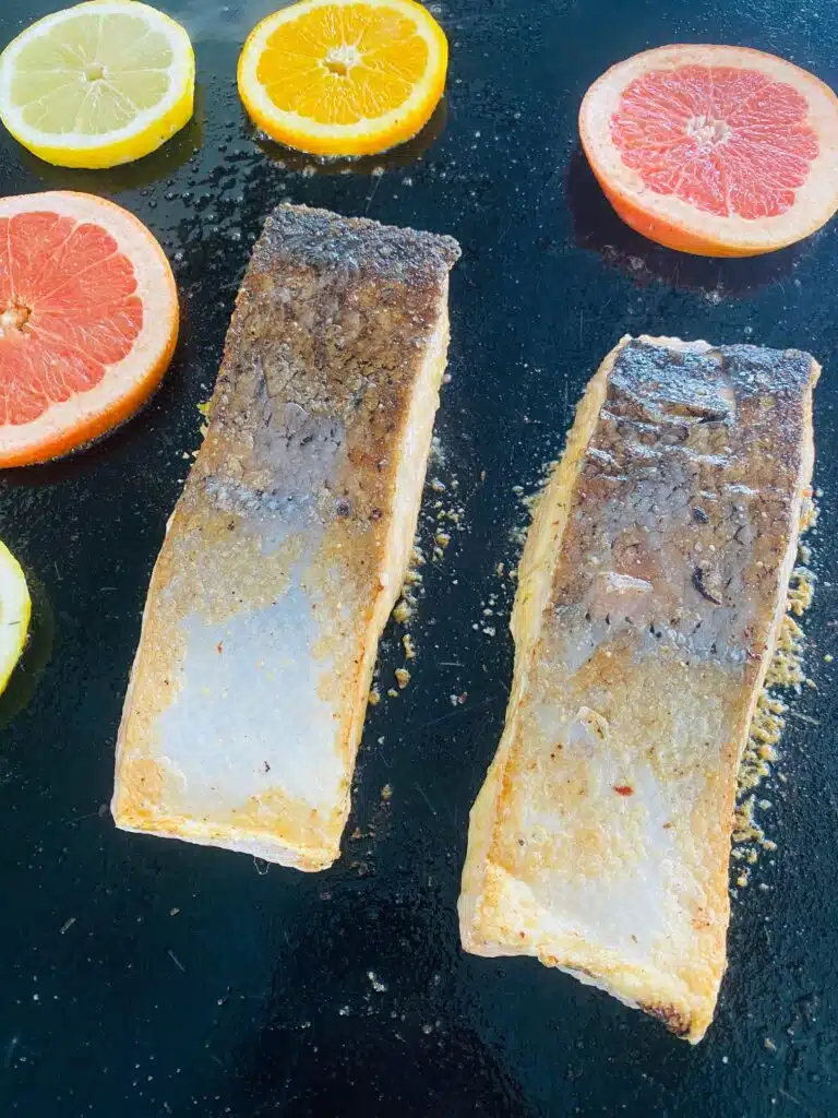 flipping the salmon and adding slices of citrus to the griddle