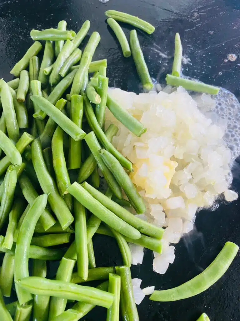 green beans and onion on the griddle before cooking