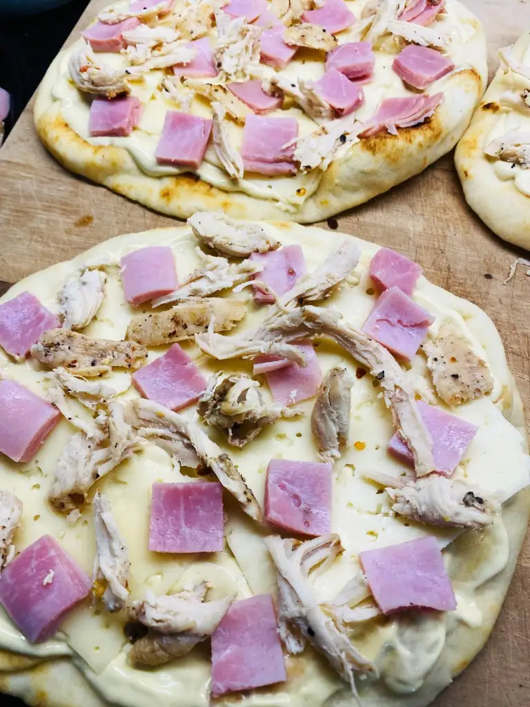 adding the ham and smoked chicken to the flatbread
