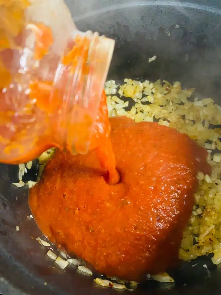 pouring the pasta sauce in the pot
