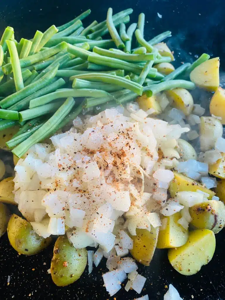 adding green beans and onions to the potatoes