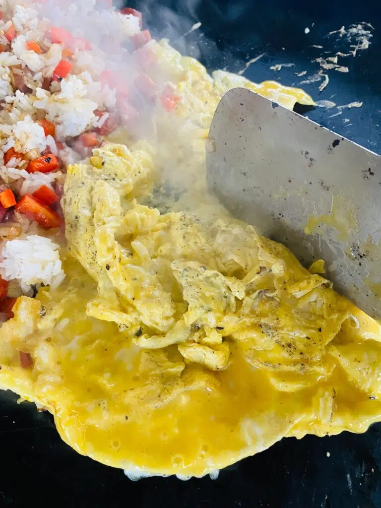 scrambling the eggs on the griddle next to the rice