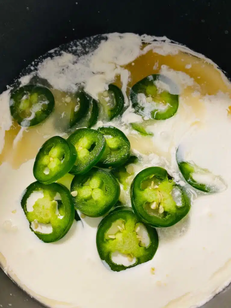adding sliced jalapenos to the sauce