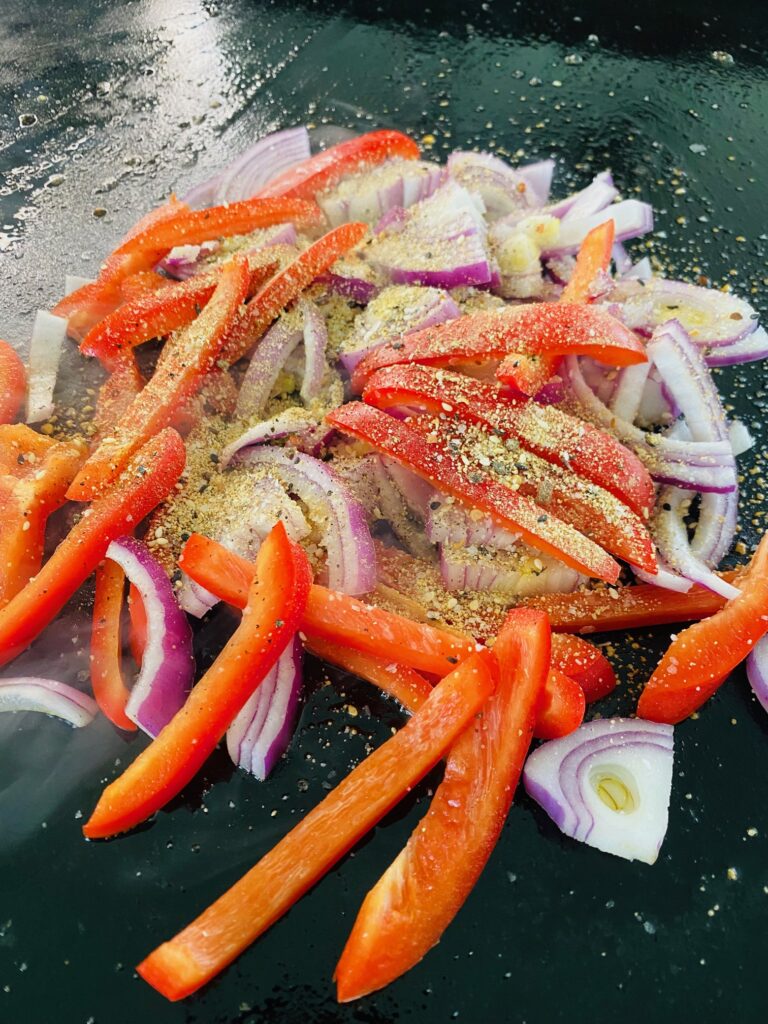 onions and peppers cooking on griddle