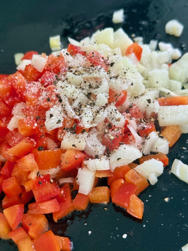 peppers and onions on griddle before cooking