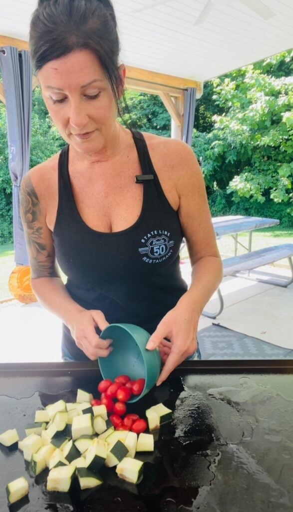 adding zucchini and tomatoes to griddle