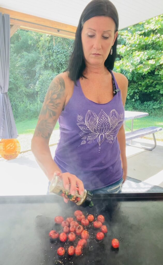 seasoning tomatoes on the griddle