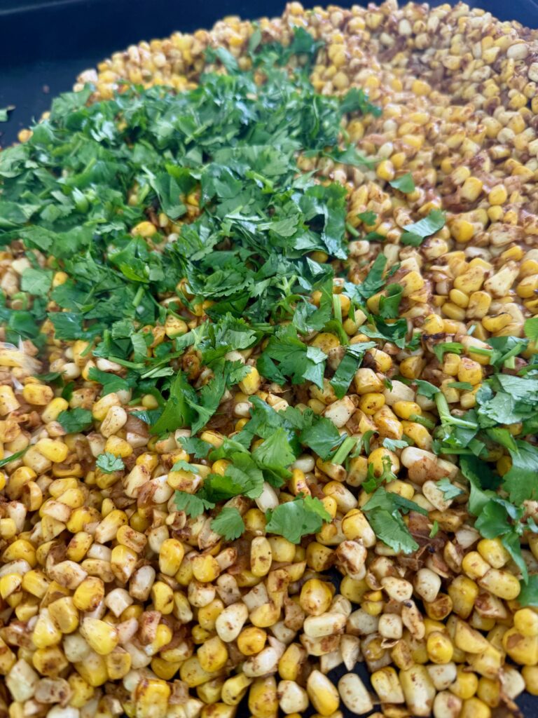 adding garlic and cilantro to corn