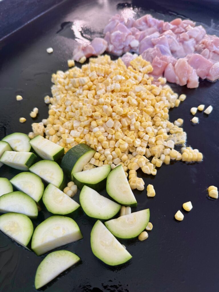 zucchini corn and chicken on griddle before cooking