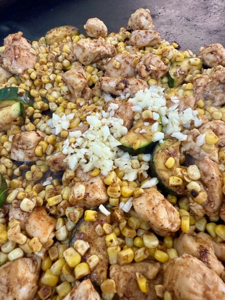 adding garlic to Blackstone Chicken Zucchini and Corn