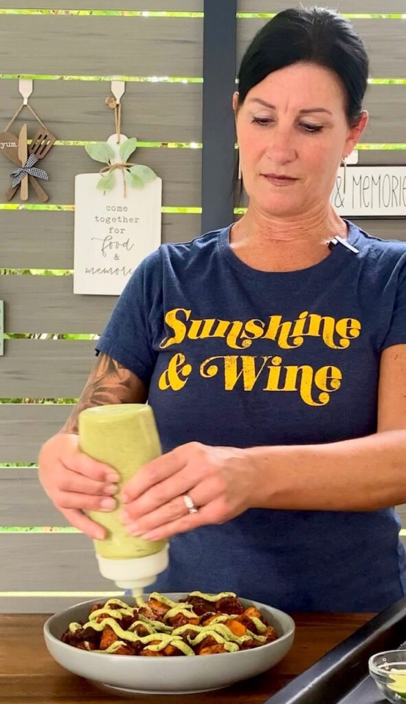 adding sauce to Blackstone Sweet Potato Chorizo Bowls