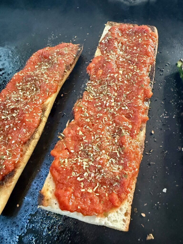 adding sauce to Blackstone Cheesy Sausage Baguettes