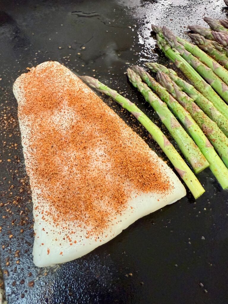 seasoned fish and asparagus on griddle before cooking