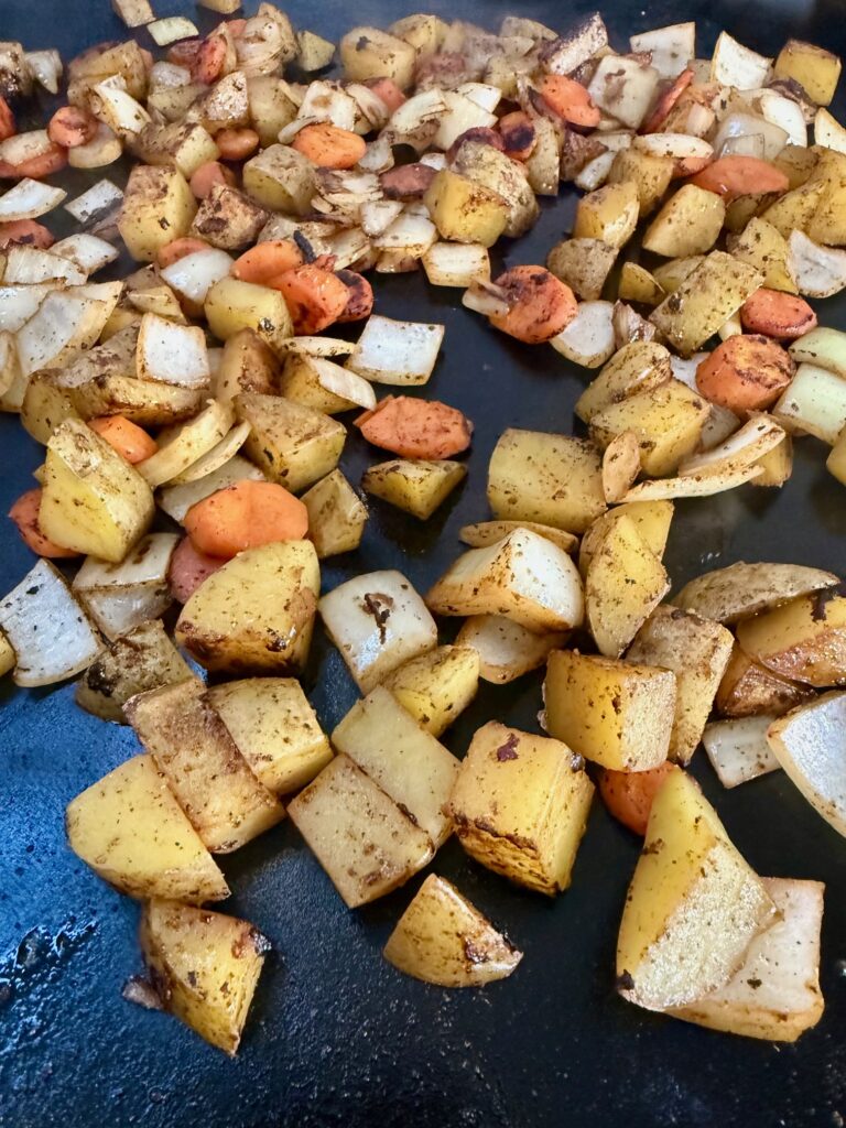 carrots onions and potatoes cooking on griddle