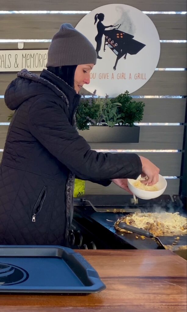 adding cheese to Blackstone Lazy Beef Enchiladas