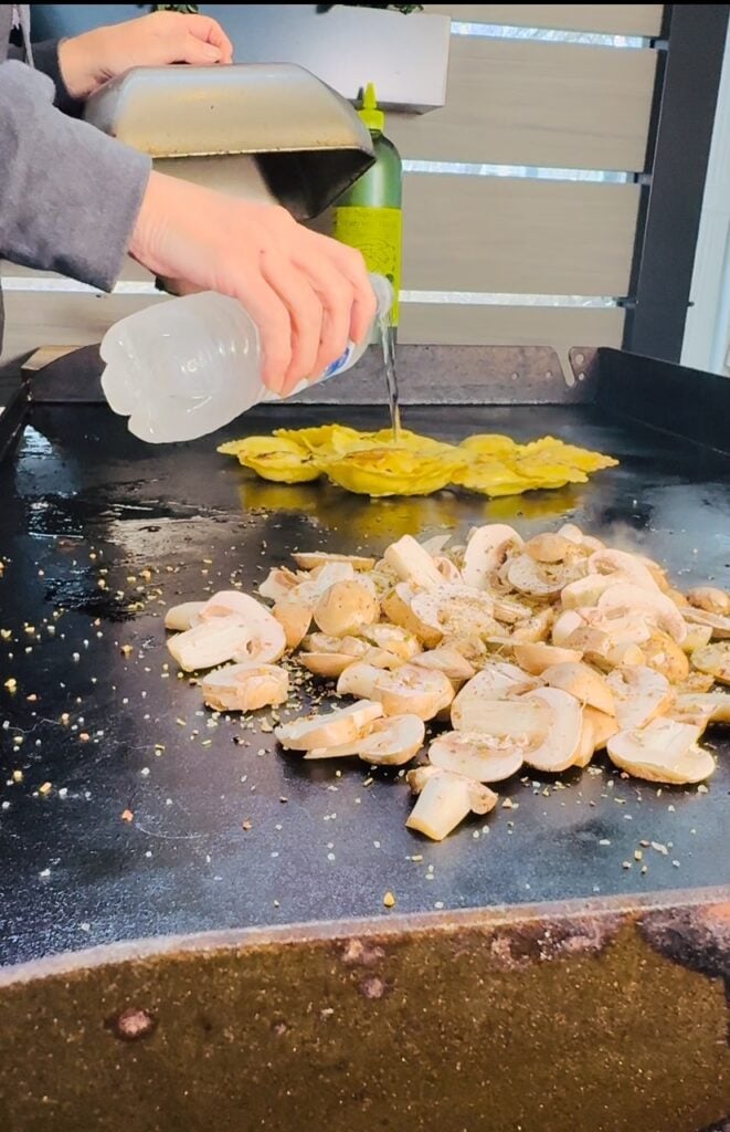 adding mushrooms and ravioli to griddle