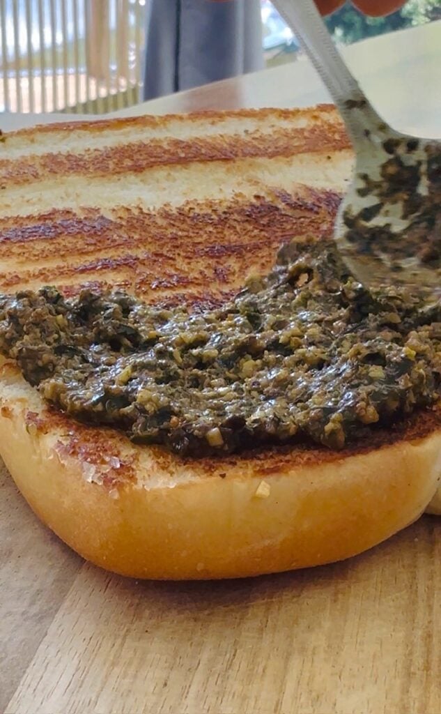 adding pesto to Blackstone Griddle Caprese Sliders