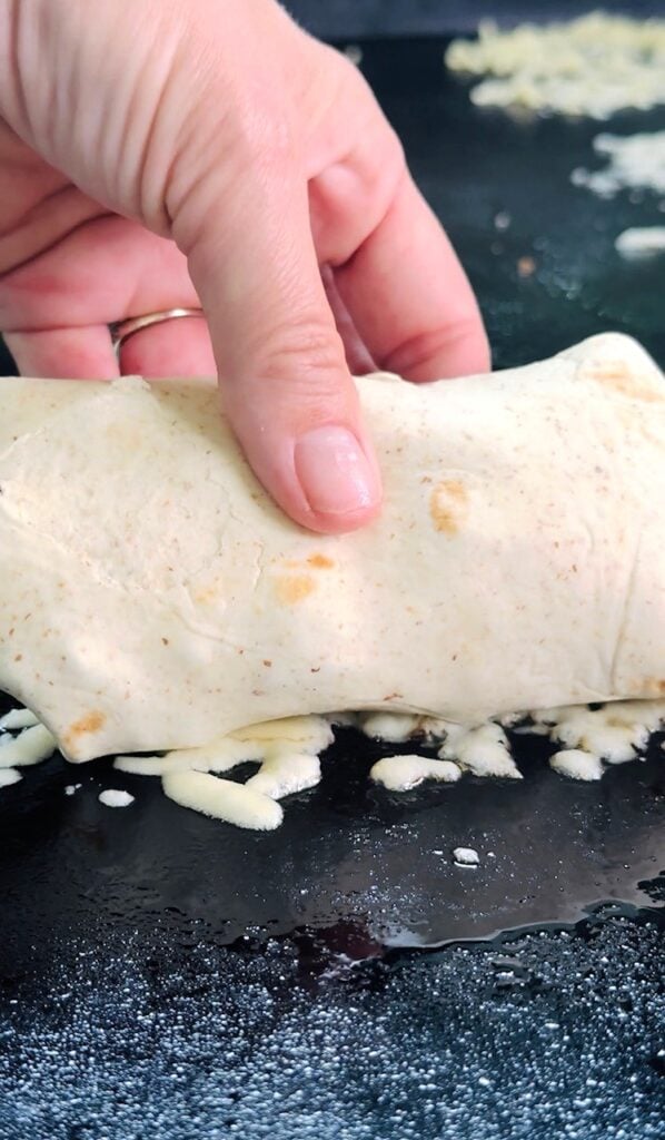 adding the wrap to the cheese on griddle