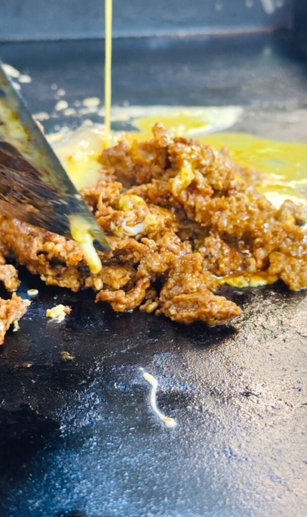 adding egg to chorizo on griddle